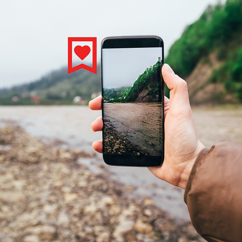 a hand holding a phone with a heart badge next to it